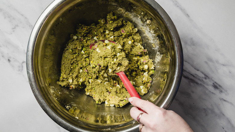 Hand stirring cold cookie batter with spatula in bowl