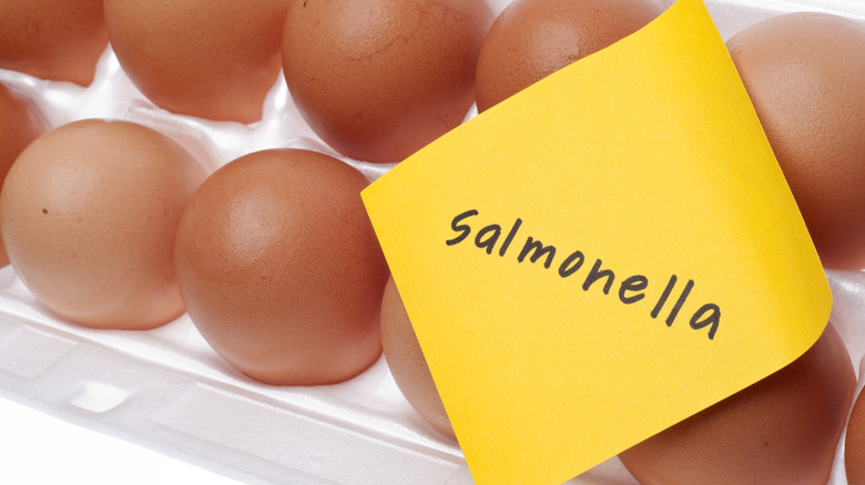 Rows of brown eggs with yellow note paper on top reading 'samonella'