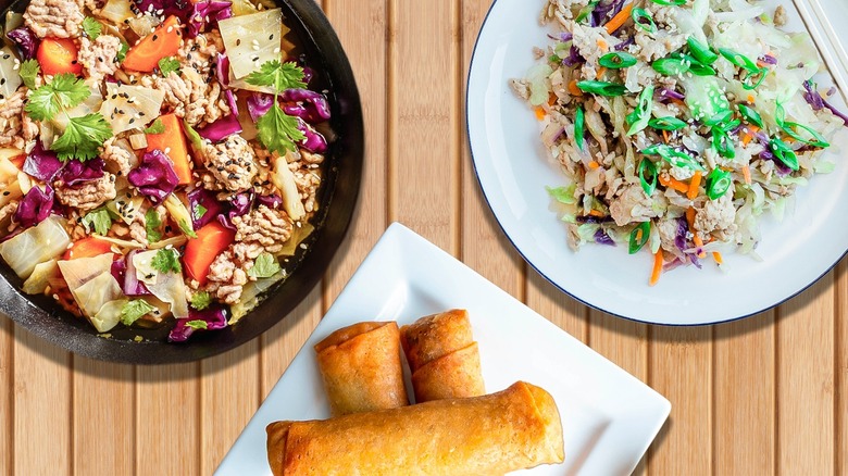 Top-down view of a plate of egg rolls and two egg roll in a bowl dishes