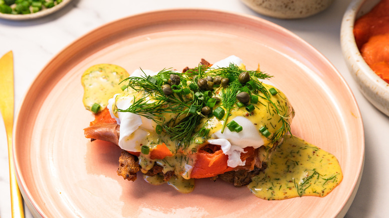 Eggs Norwegian with rosti and dill hollandaise on a pink plate.
