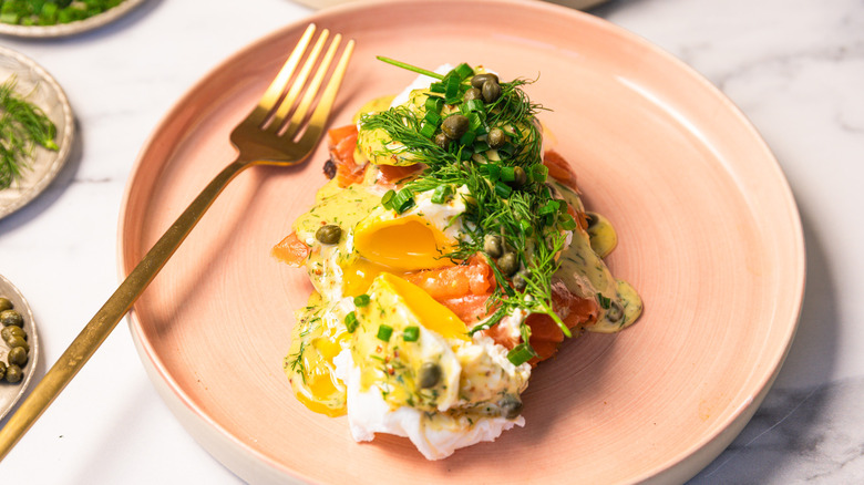Close up on cut egg from eggs Norwegian with rosti and dill hollandaise on a pink plate.