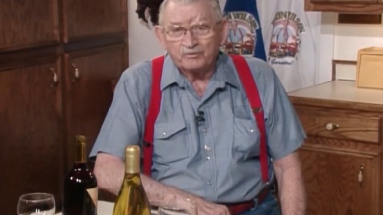 Justin Wilson sitting at a table with a bottle of wine