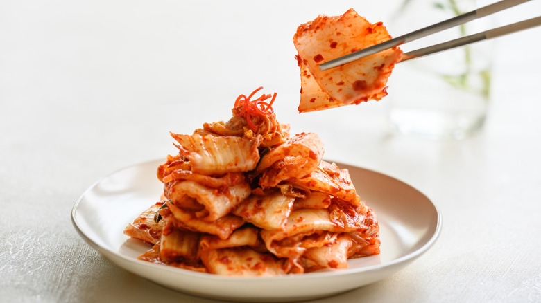 Chopstick picking up kimchi from a dish