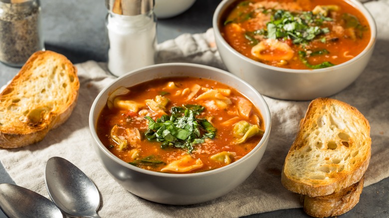 A bowl of tortellini soup and bread slices
