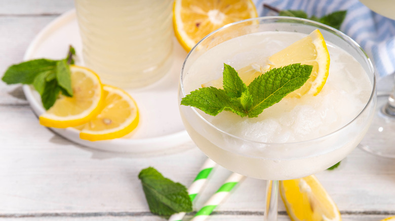 Lemon drop cocktail with lemon wedges and mint leaves