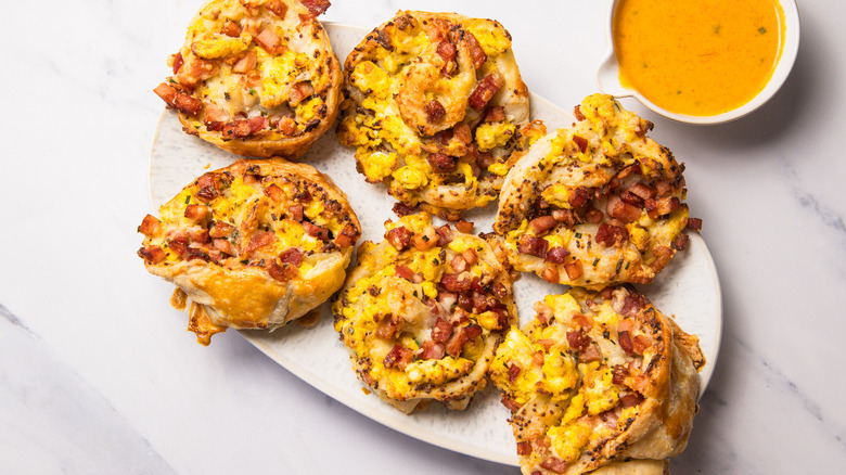 Six eggs Benedict rolls on a plate with hollandaise sauce