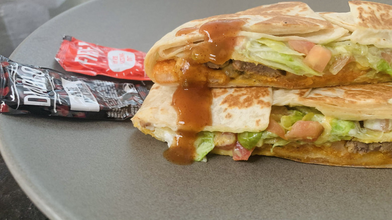 California Crunchwrap cut in half and stacked on each other with hot sauce poured over one side
