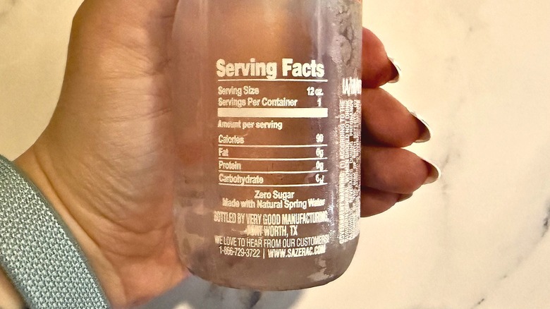 Hand holding bottle of Svedka vodka water showing nutrition facts