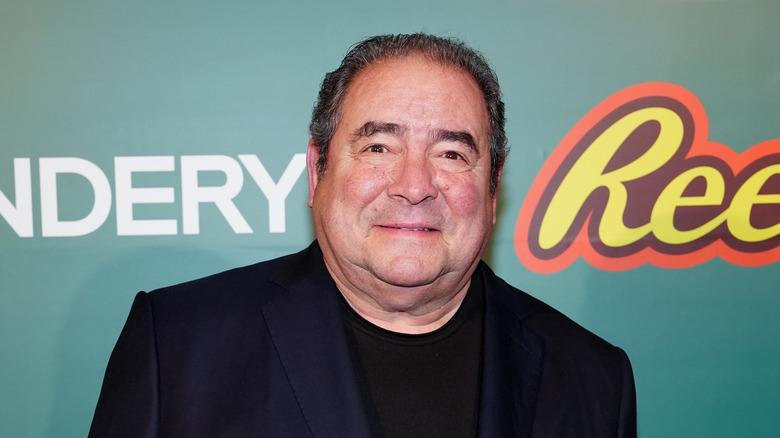 Chef Emeril Lagasse smiling against teal background