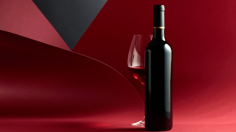 Bottle of wine and glass on red background