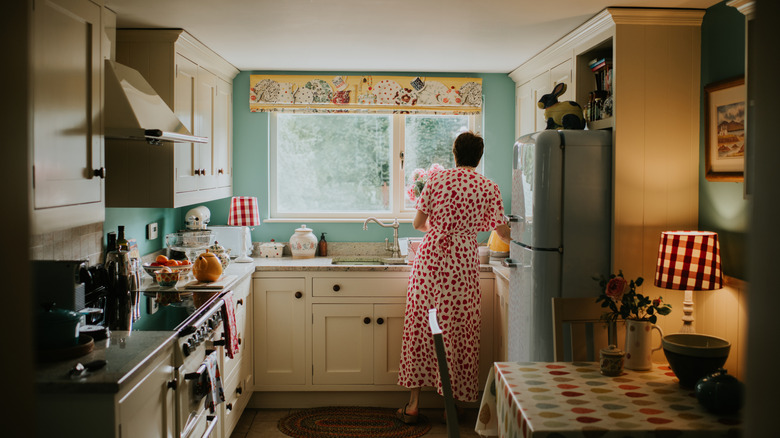 Woman arranges flowers at the sink in a cozy kitchen