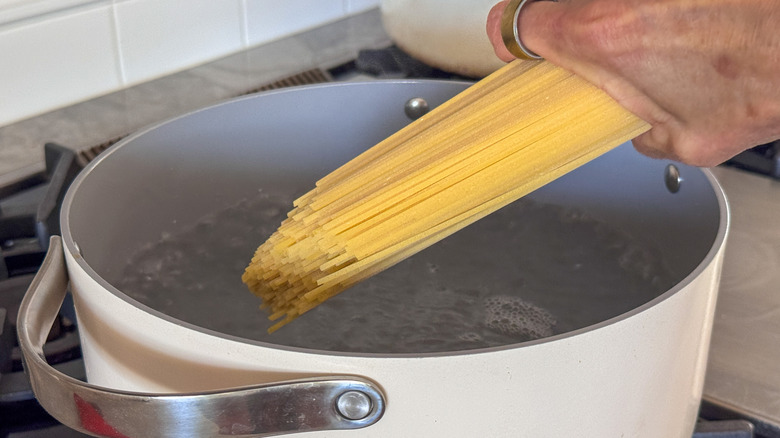 hand adding pasta to pot
