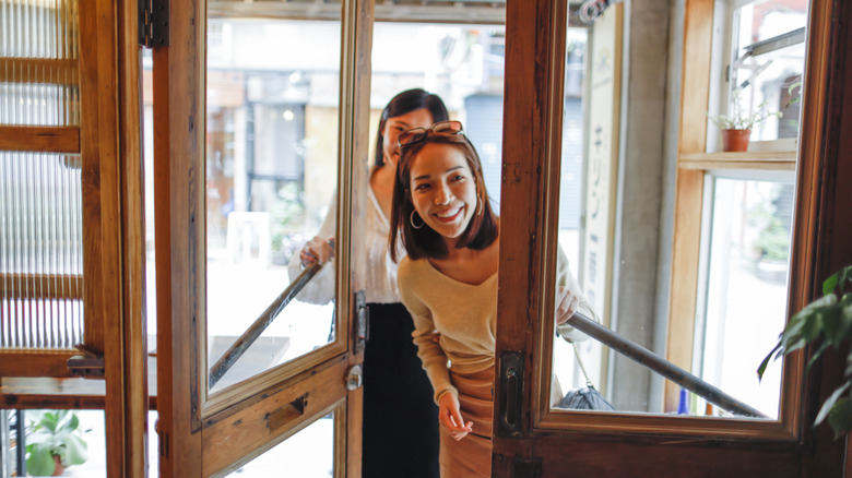 Two women walking curiously into the front doors of a restaurant