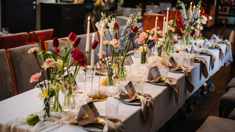 Lavish restaurant party table set with candles, fresh flowers, and place settings