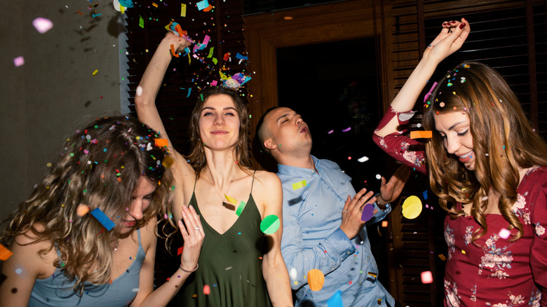 Birthday party guests dancing while surrounded by flying confetti