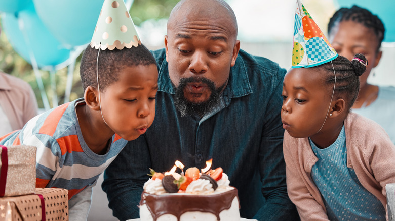 Father with his son and daughter blowing out birthday candles