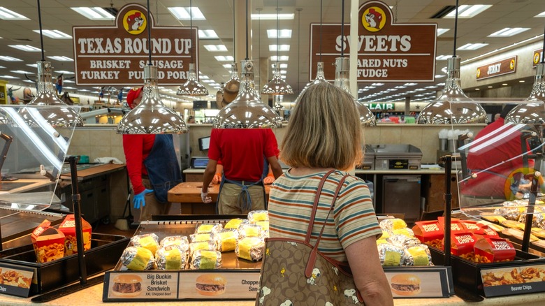 Prepared foods counter inside Buc-ee's store with employees behind counter and woman browsing items