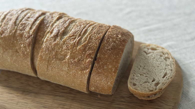 Loaf of sourdough bread on a wooden cutting board with slices cut