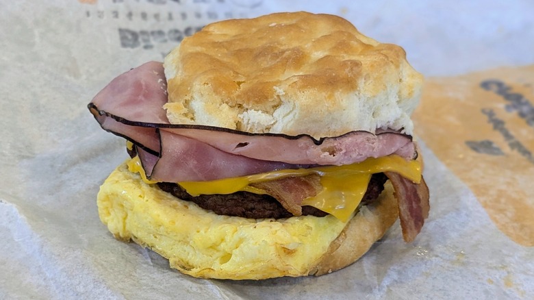 A bacon, ham, sausage, egg, and cheese biscuit on a fast food wrapper