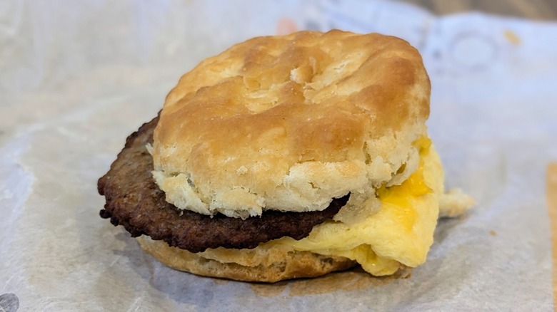 A sausage, egg, and cheese biscuit on a fast food wrapper
