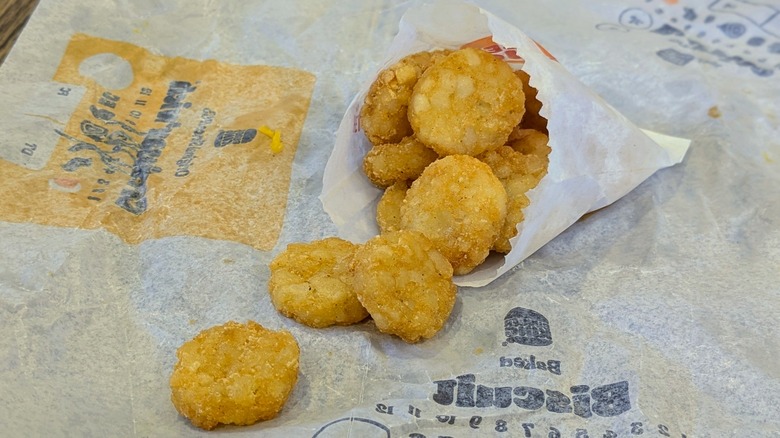 A small pile of hash brown medallions spilling from a paper bag