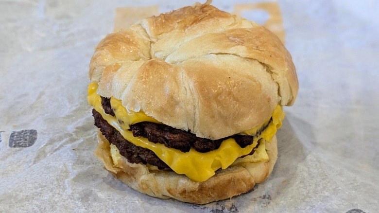 A double sausage, egg, and cheese croissant on a fast food wrapper