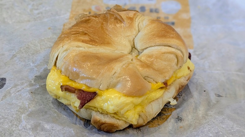 A bacon, egg, and cheese croissant on a fast food wrapper