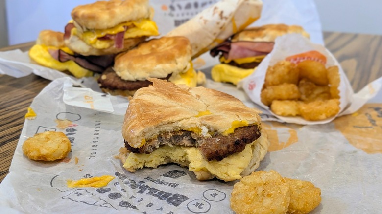 A breakfast sandwich with a bite taken out and other breakfast items in the background