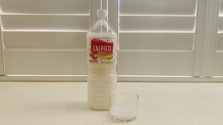 bottle of Calpico White Peach beside a half-filled glass