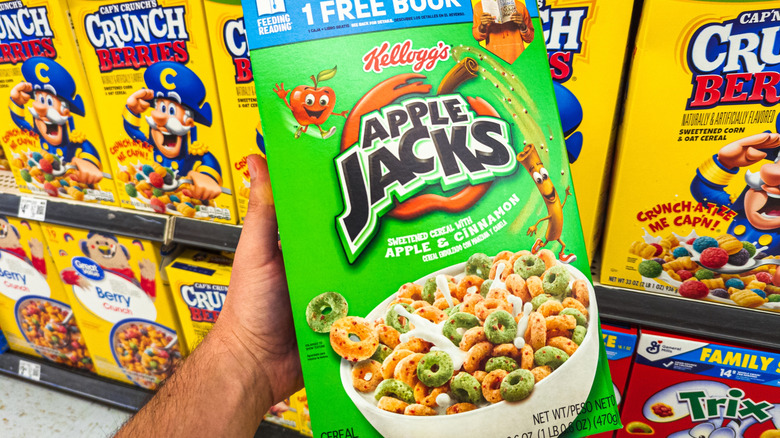 Hand holding box of Apple Jacks cereal on grocery store