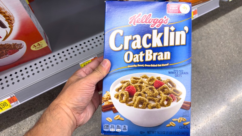 Hand holding box of Cracklin' Oat Bran cereal in grocery store
