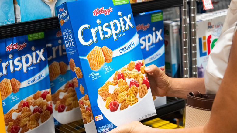 Hands holding box of Crispix cereal in grocery store