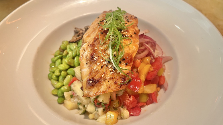 Salmon bowl with veggies and edamame topped with greens and sesame seeds