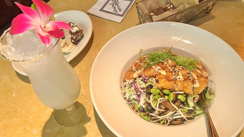Katsu bowl with flower-decorated drink and bread in background