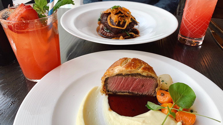Steak Wellington served at Gordon Ramsay's restaurant with mash, veggies, and cocktail on the side