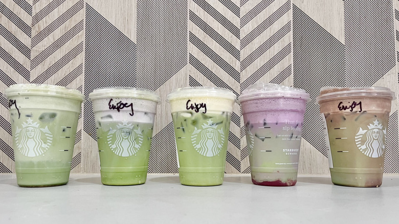 Various flavored matcha drinks lined up on a table
