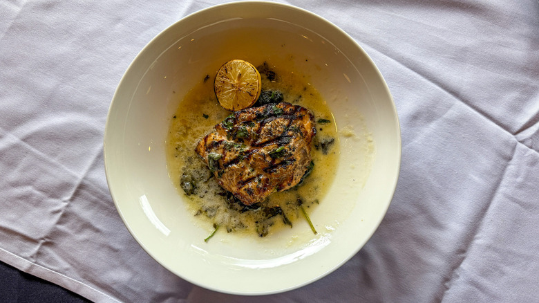 Grilled salmon plated on bed of spinach with lemon