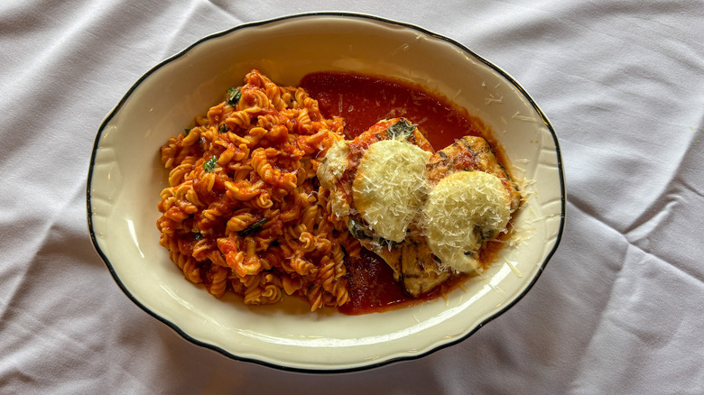 Plate of grilled chicken topped with mozzarella cheese and a side of gluten-free pasta