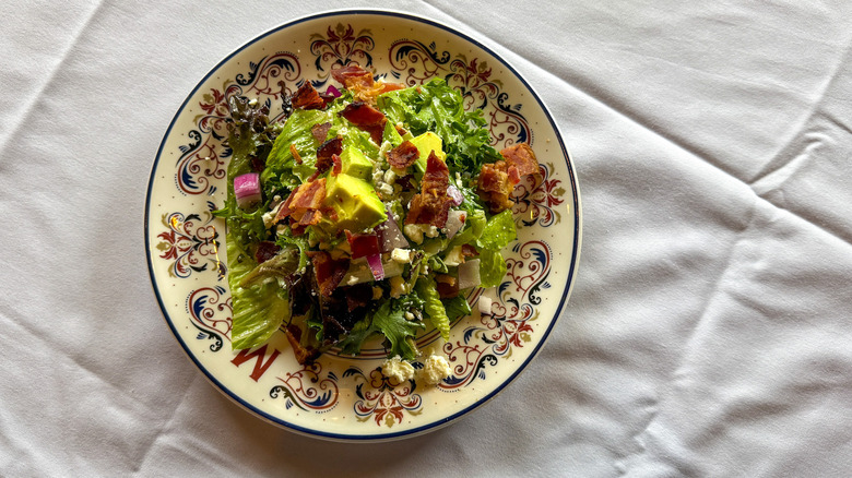 Salad with bacon, blue cheese, and avocado on a patterned plate