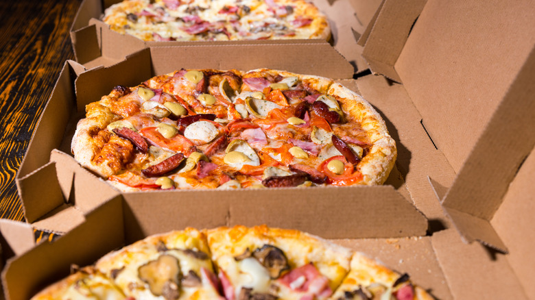 Close up of three different pizzas in to-go boxes