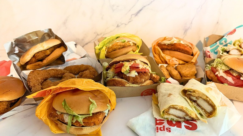 Several McDonald's chicken sandwiches, strips, and nuggets on marble background