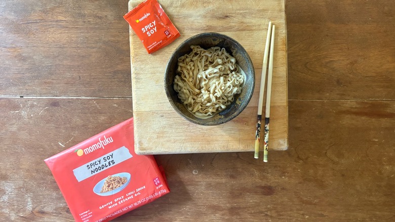 A bowl of noodles on a wooden cutting board