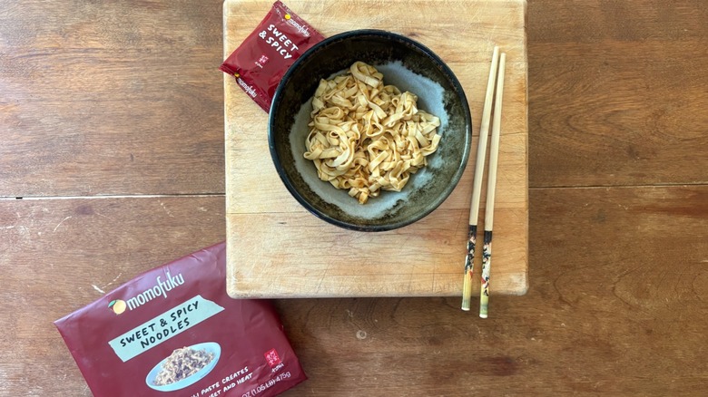 A bowl of noodles on a wooden cutting board