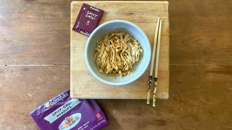A bowl of noodles on a wooden cutting board