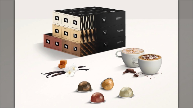 Nespresso Barista Creations Flavor Pack next to two coffee mugs, coffee pods, and flavorings on white surface