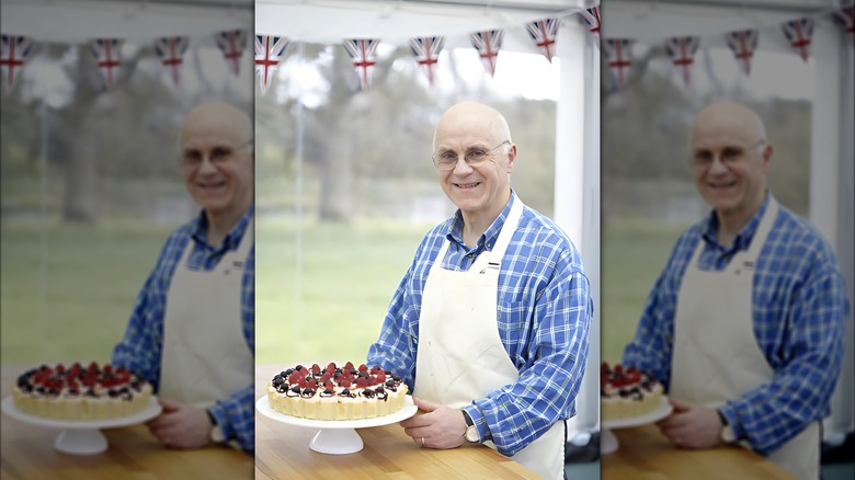 GBBO Series 3 contestant Brendan Lynch in apron proudly presenting a berry-topped cake on a stand