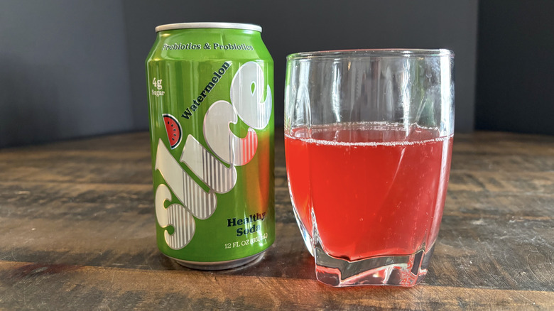 Slice watermelon soda in can and glass on wooden table with black background