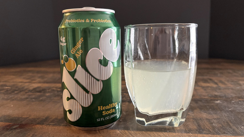 Slice ginger ale in can and glass on wooden table with black background