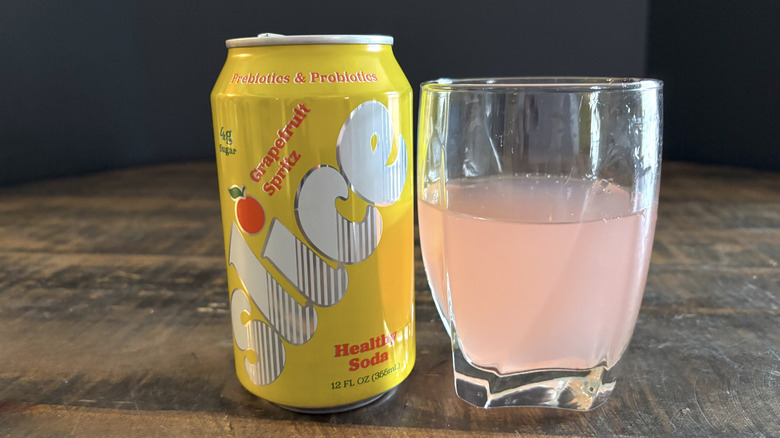 Slice grapefruit spritz soda in can and glass on wooden table with black background