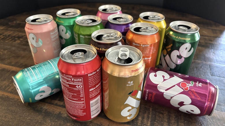 A variety of Slice soda cans on a wooden table and black background